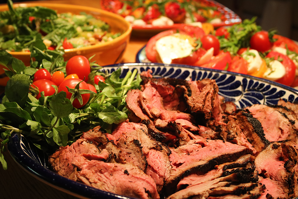 sugar steak on a mexican platter with fresh herbs and cherry tomato garnish and in the background tomato mozzarella platter