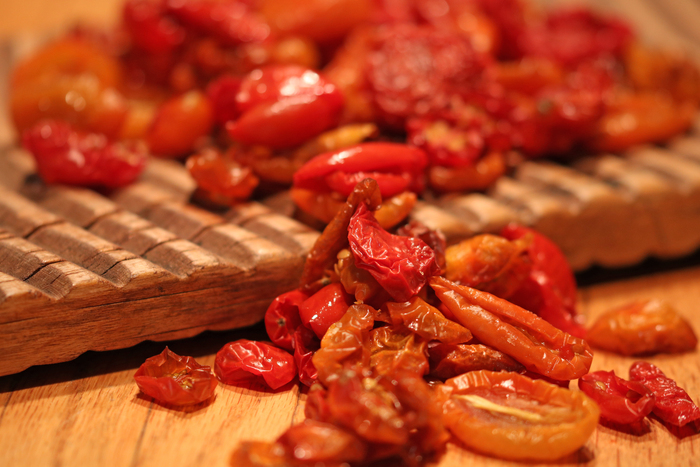wooden board with dried red and yellow cherry tomatoes spilling on wooden counter