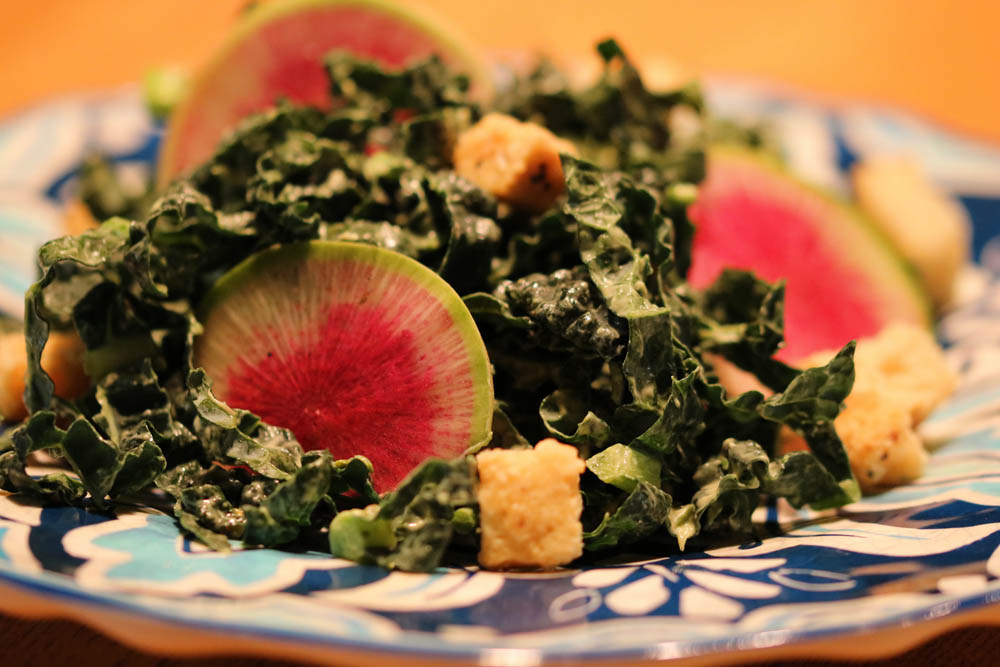 Kale with Creamy Green Goddess and Watermelon Radish on a blue patterned plate