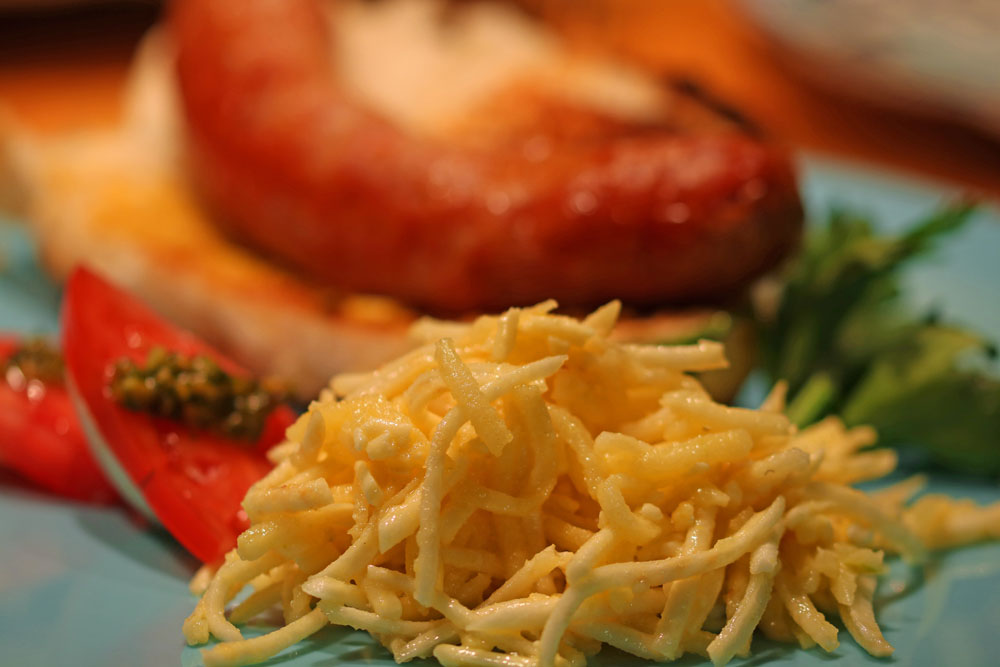 Creamy Apple, Cheddar Celery Root Slaw with a brat in the back