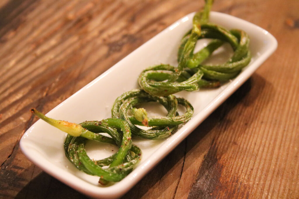 Roasted Garlic Scape bundles on a white rectangular dish on a wooden table