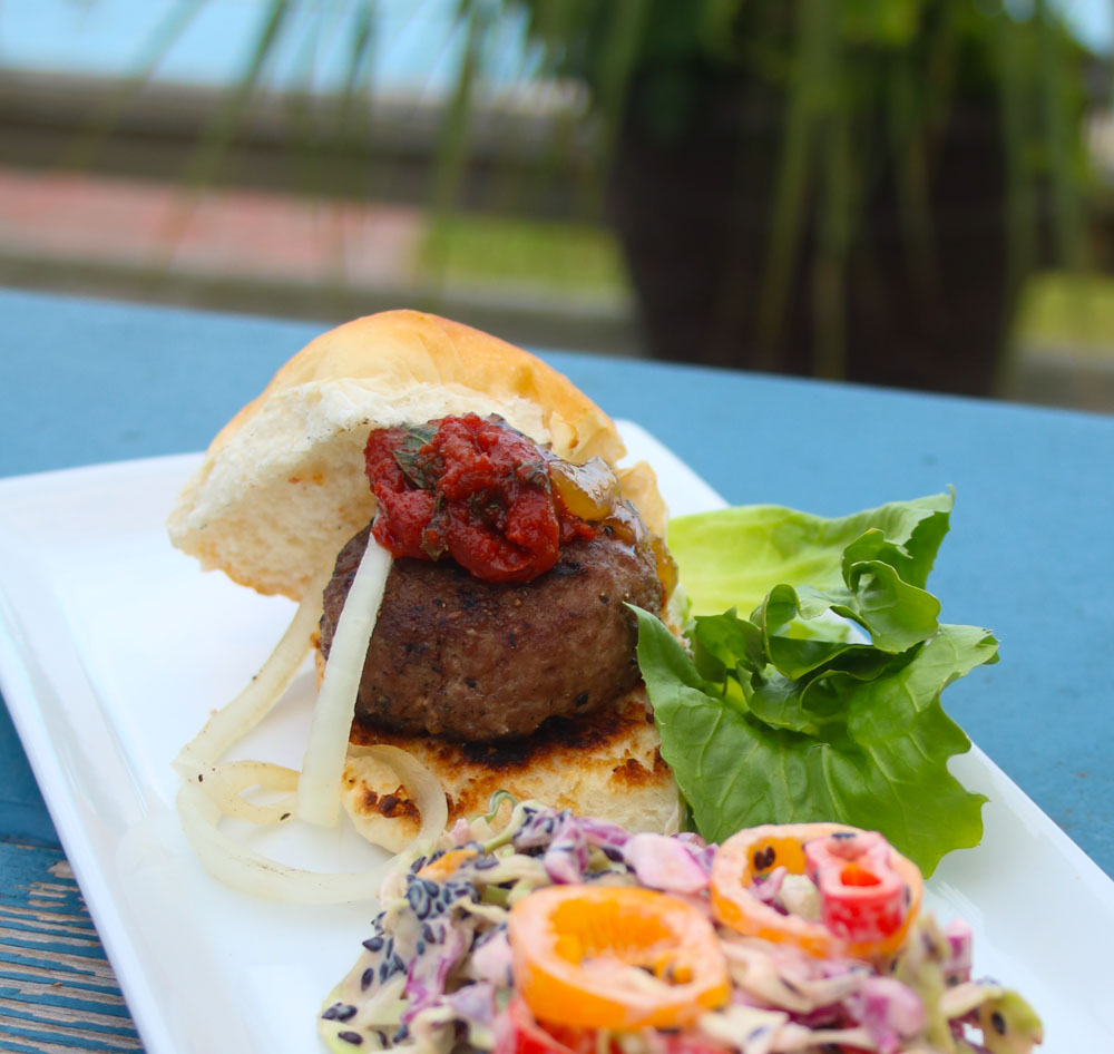 Lamb Slider with Smoked Tomato Mint Jam and slaw on a white rectangular plate