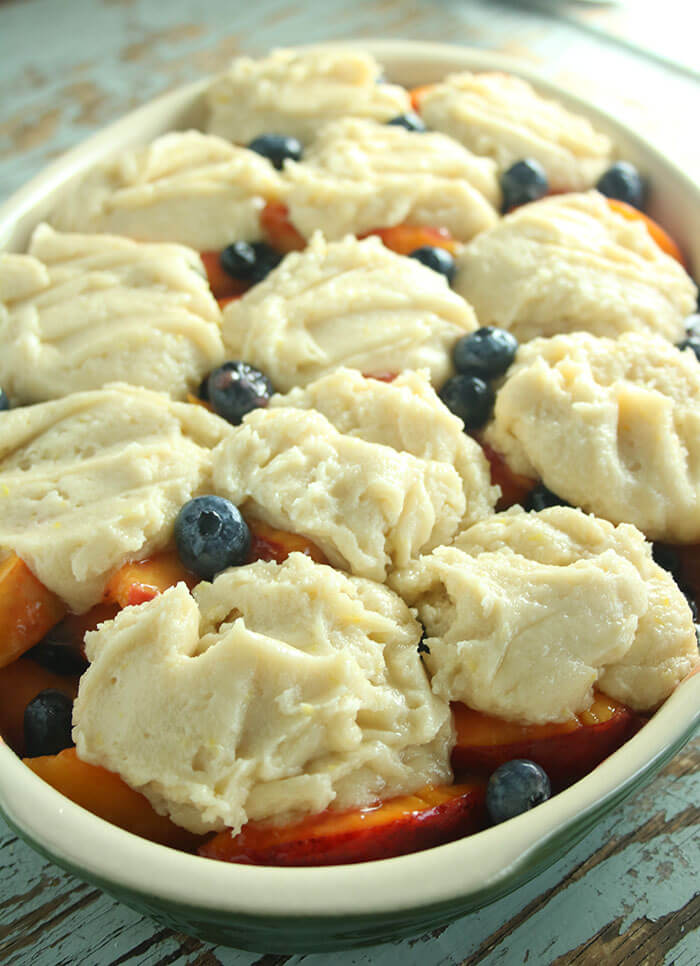 Adding Biscuit dough atop Summer Fruit in an oval casserole
