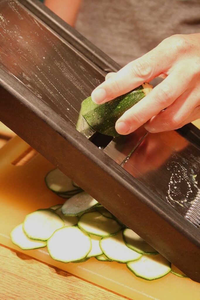 Thinly slicing squash on a mandoline