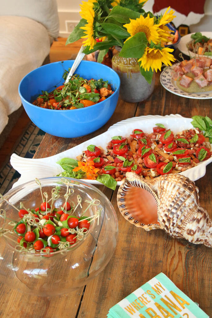 Tomatoes Three Ways: in a bowl with panzenlla, skewered caprese salad and as bruschetta topping with a pitcher of sunflowers