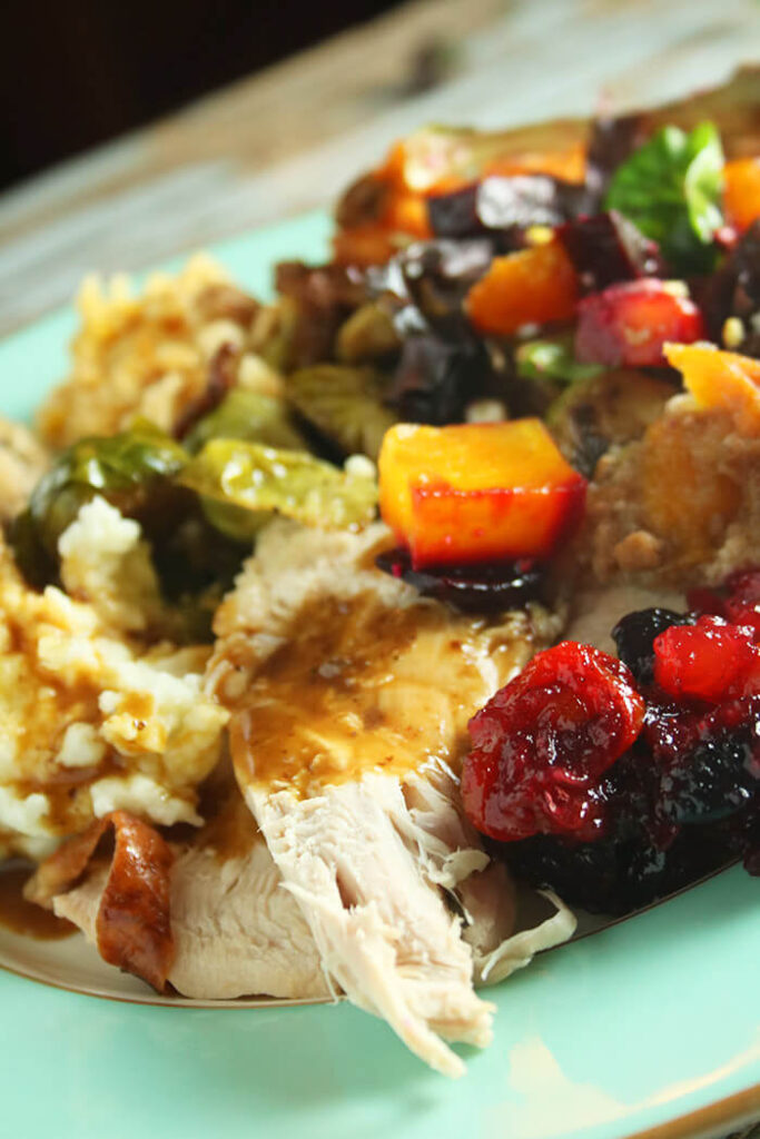 Blue plate with turkey, gravy, mash potatoes, stuffing, brussels sprouts, chuntey and salad