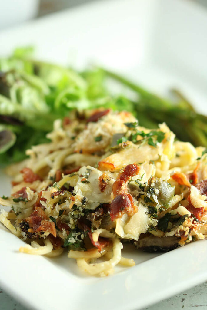 Heaping Helping turkey tetrazzini on a square white plate with a salad