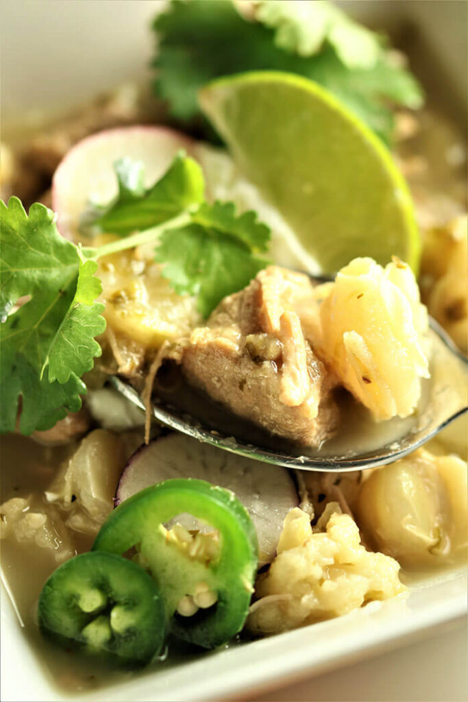 spoonful of pork and polose with lime and cilantro garnish