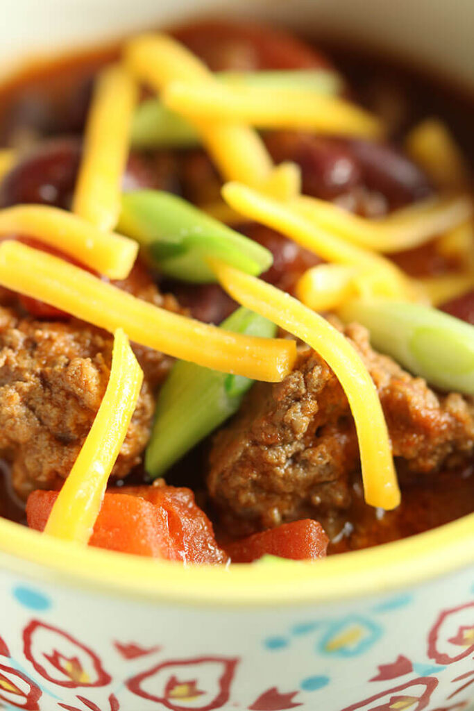 Kick Off Chili with All the Toppings - close up with tomatoes, scallions and grated cheddar