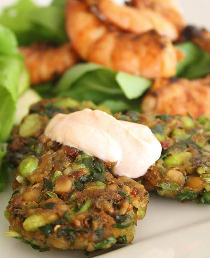 Edamame & Chickpea Fritters close up with chipotle sauce and shrimp behind