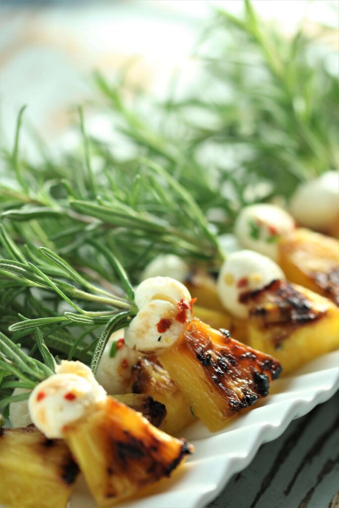 Fresh Mozzarella and Grilled Pineapple Brochettes skewered on rosemary branch