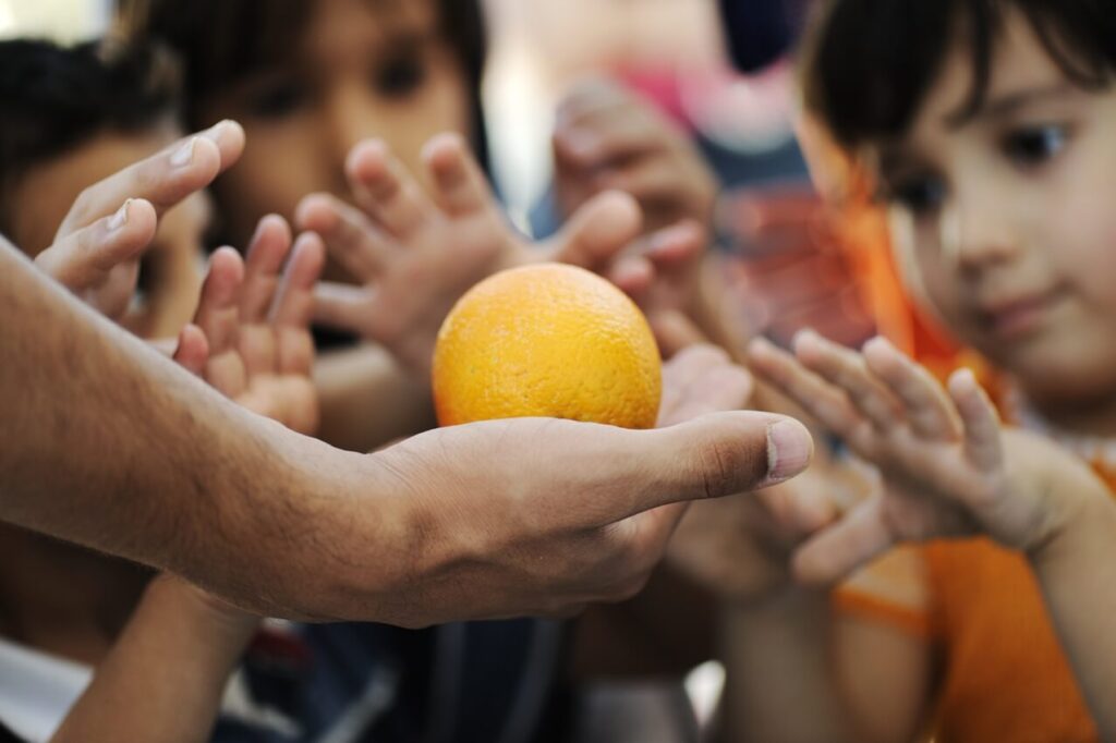 Hunger Hits the Most Vulnerable; Many hands reach for one orange