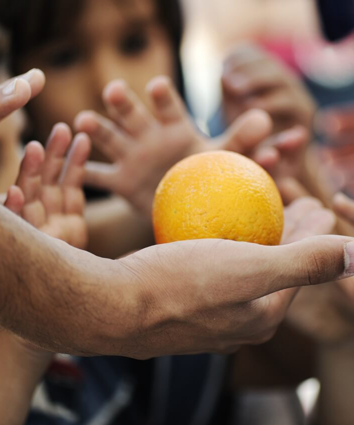 Hunger - many hands reach for one orange