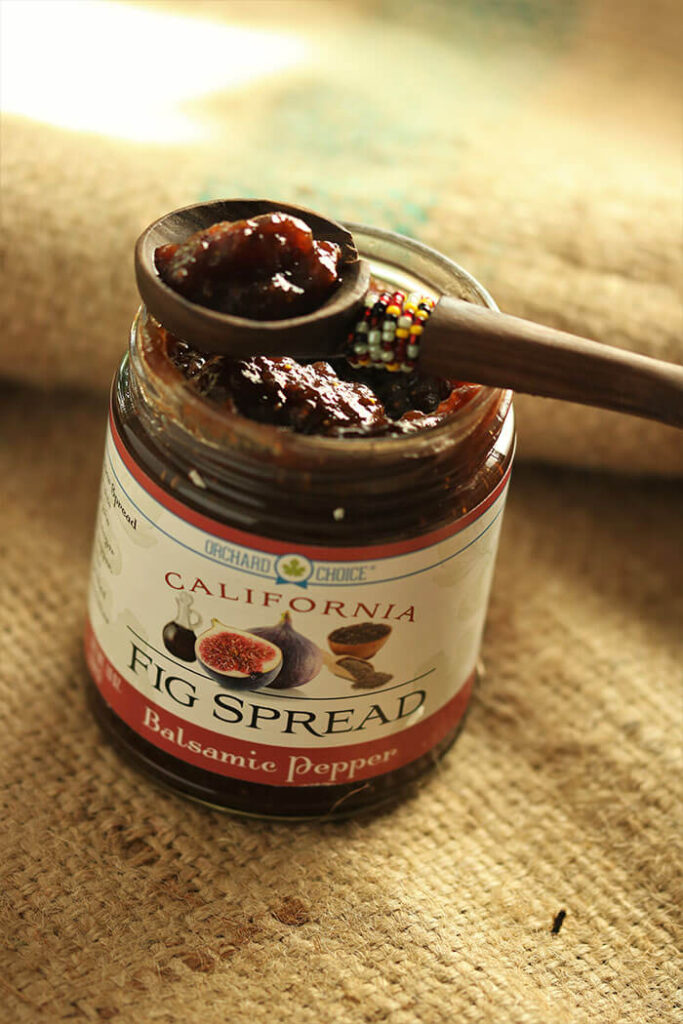 Balsamic Pepper Fig Spread in a jar with a wooden spoon on burlap