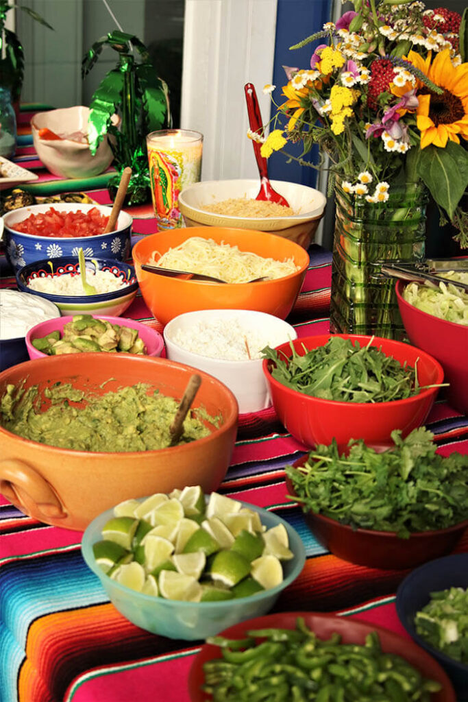 Dinner\'s Done - condiments for fajita party - lime, guacamole, cilantro, sour cream, queso, salsa served on a serape