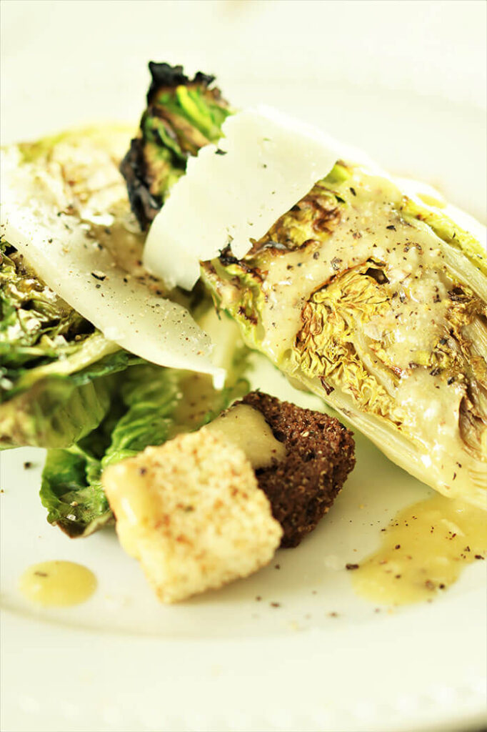 Grilled Caesar Salad with cheese and croutons on white plate