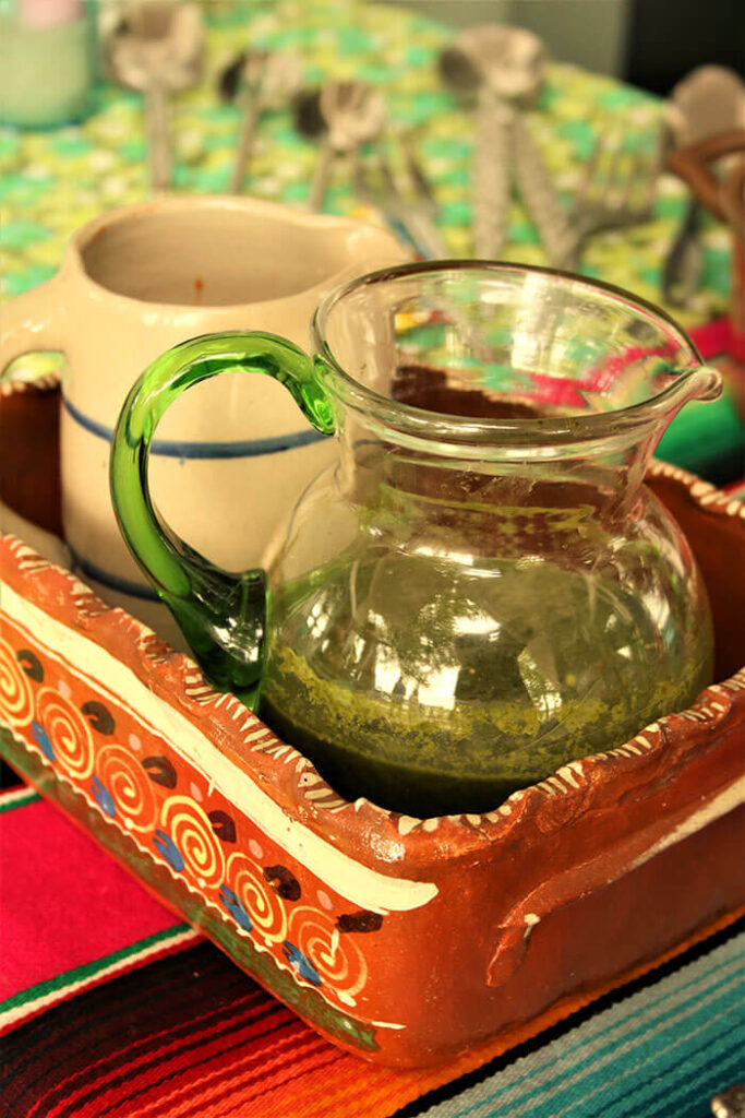 Salsa Verde and Salsa Roja in pitchers in a mexican terracotta tray