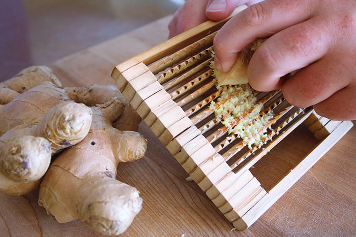 Grating Ginger by hand on a wooden grater
