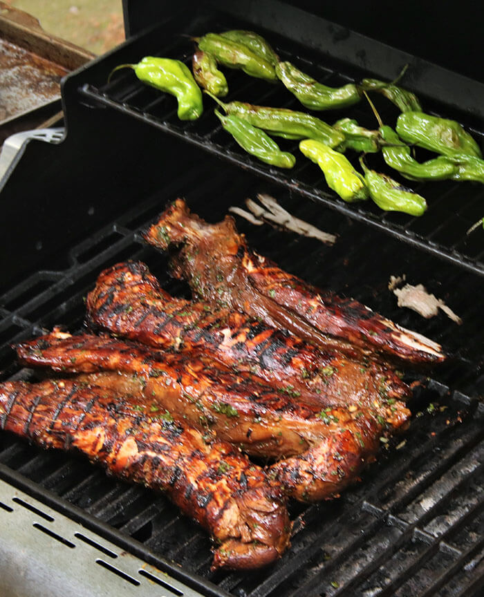 Asian Marinated Pork on the grill with shishito pepper above