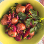 Overhead shot of green bowl filled with  Roasted Potato Salad with tomatoes, oven dried tomatoes, bacon and edamame