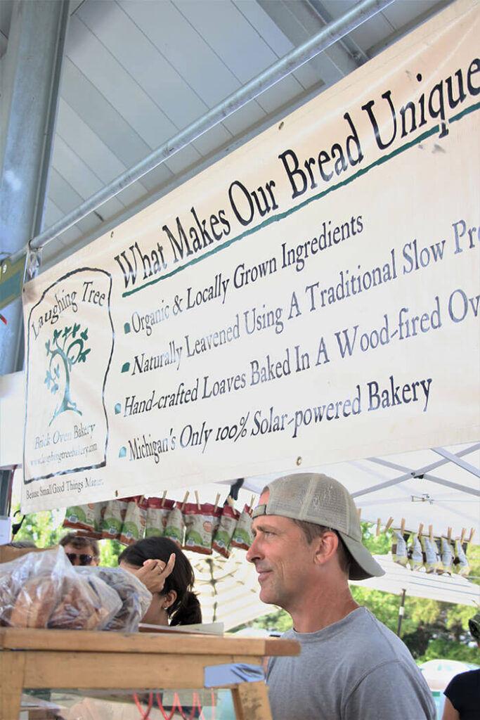 What Makes Our Breads Unique - farmers market sign with Charlie Muller