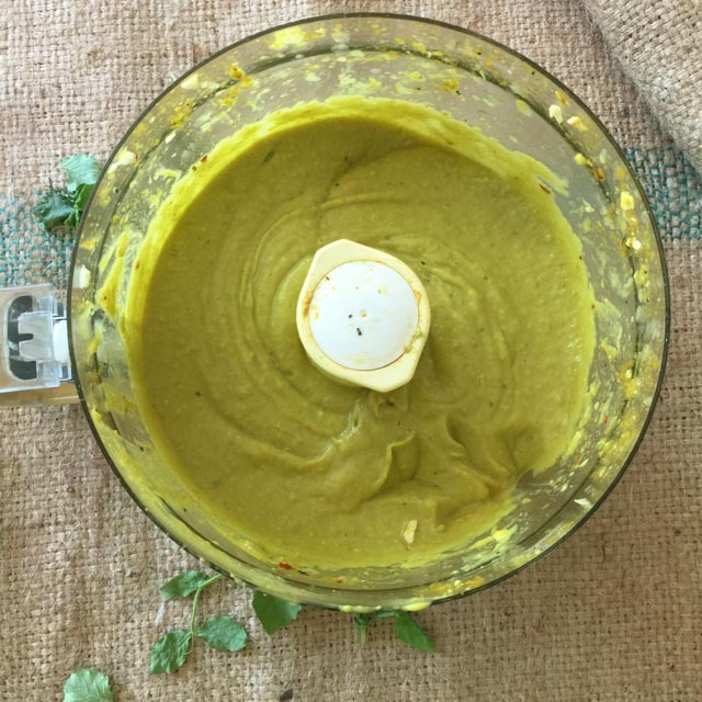 Creamy Curried Avocado Dressing in a food processor work bowl on burlap