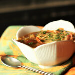 3 Onion Soup in a scalloped edge white bowl with a spoon