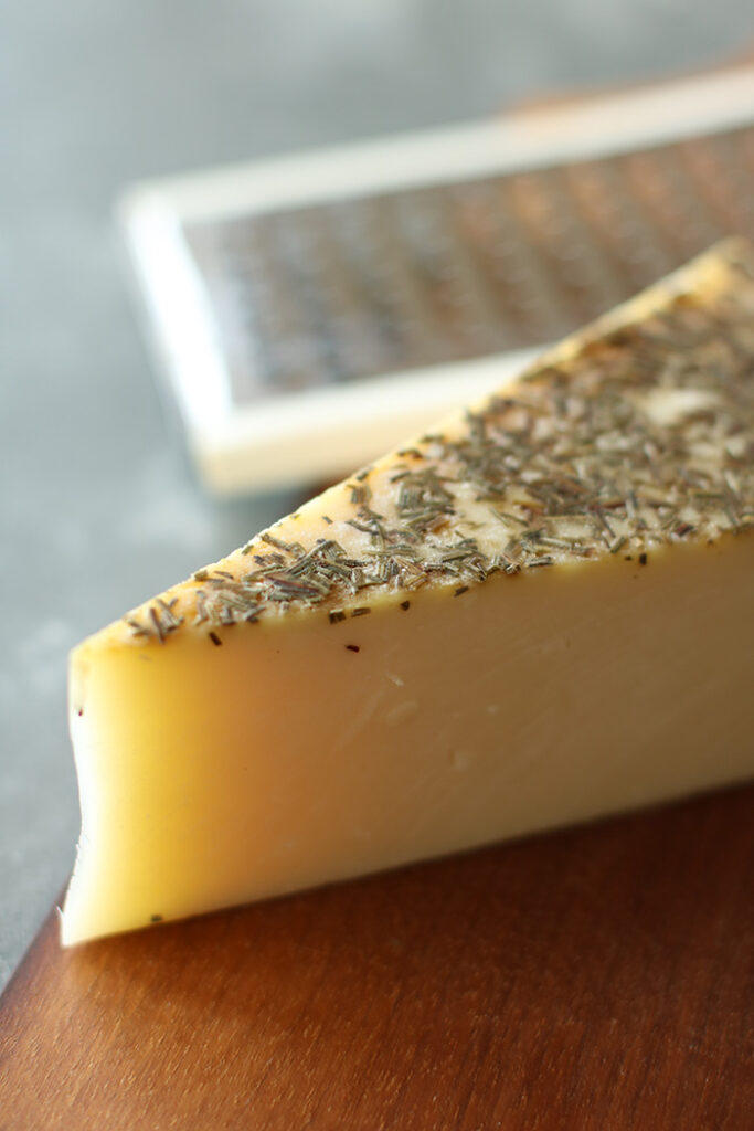 Rosemary Asiago Wedge on a cutting board with grater in the background