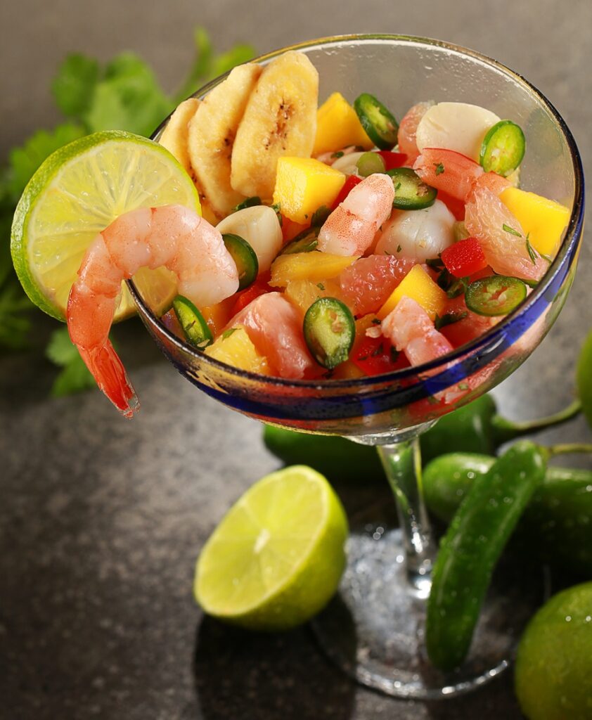 Margarita glass with shrimp ceviche with mango, grapefruit , jalapanos and plantain chips, garnished with lime
