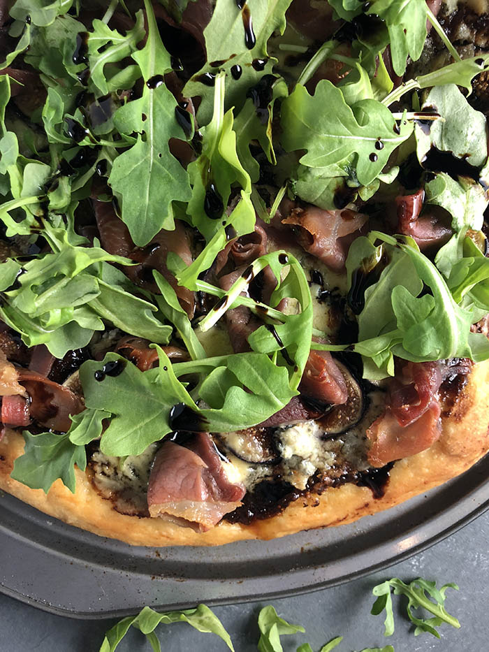 Arugula atop a fig prosciutto pizza