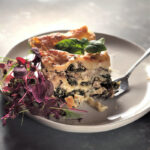 Shiitake Kale Lasagna on a white plate with a fork and micro green salad