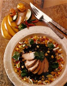 Pork tenderloin, fanned out on black beans and citrus salsa with knife and fork