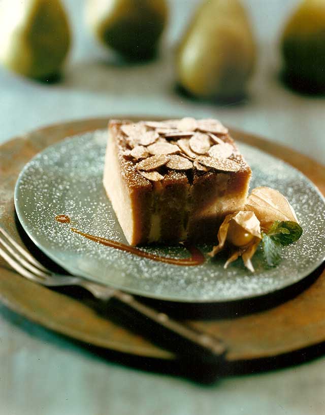 slice of bread pudding with pears and almonds garnished with a cape gooseberry and dusted with powdered sugar