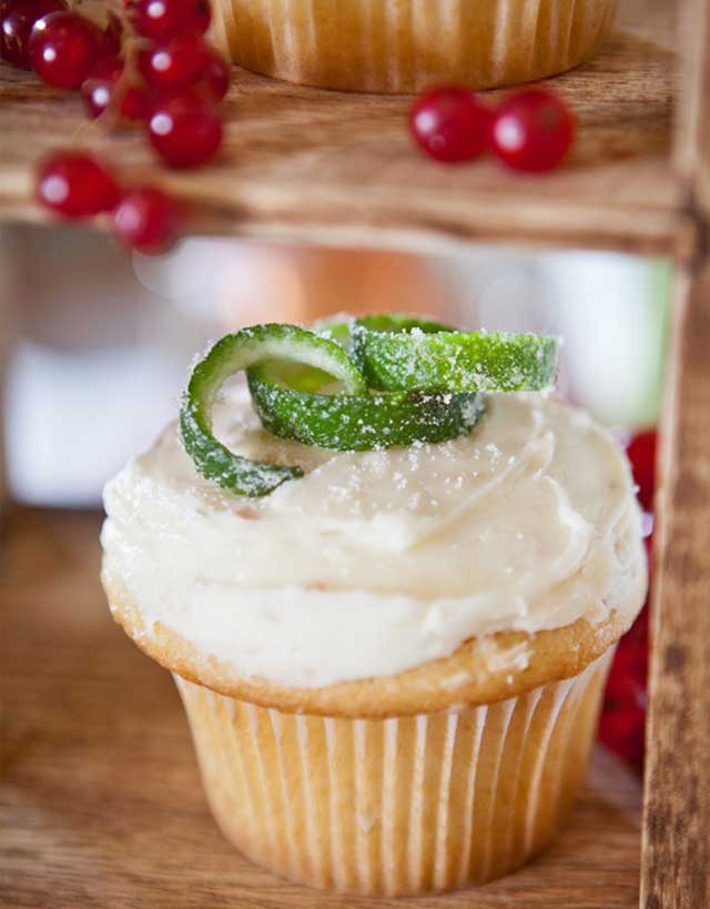 Cupcake with white frosting and sugar pears, garnished with candied lime strips and red currants
