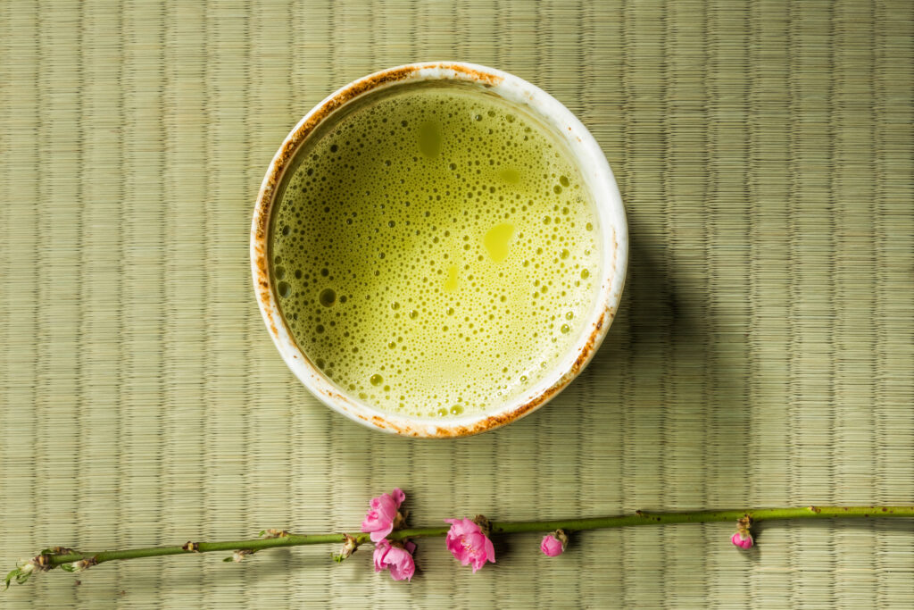 Green mat with ceramic bowl of matcha with cherry blossom